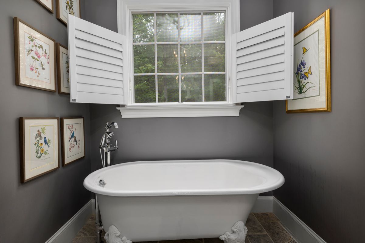 White louvred shutters above a freestanding bathtub