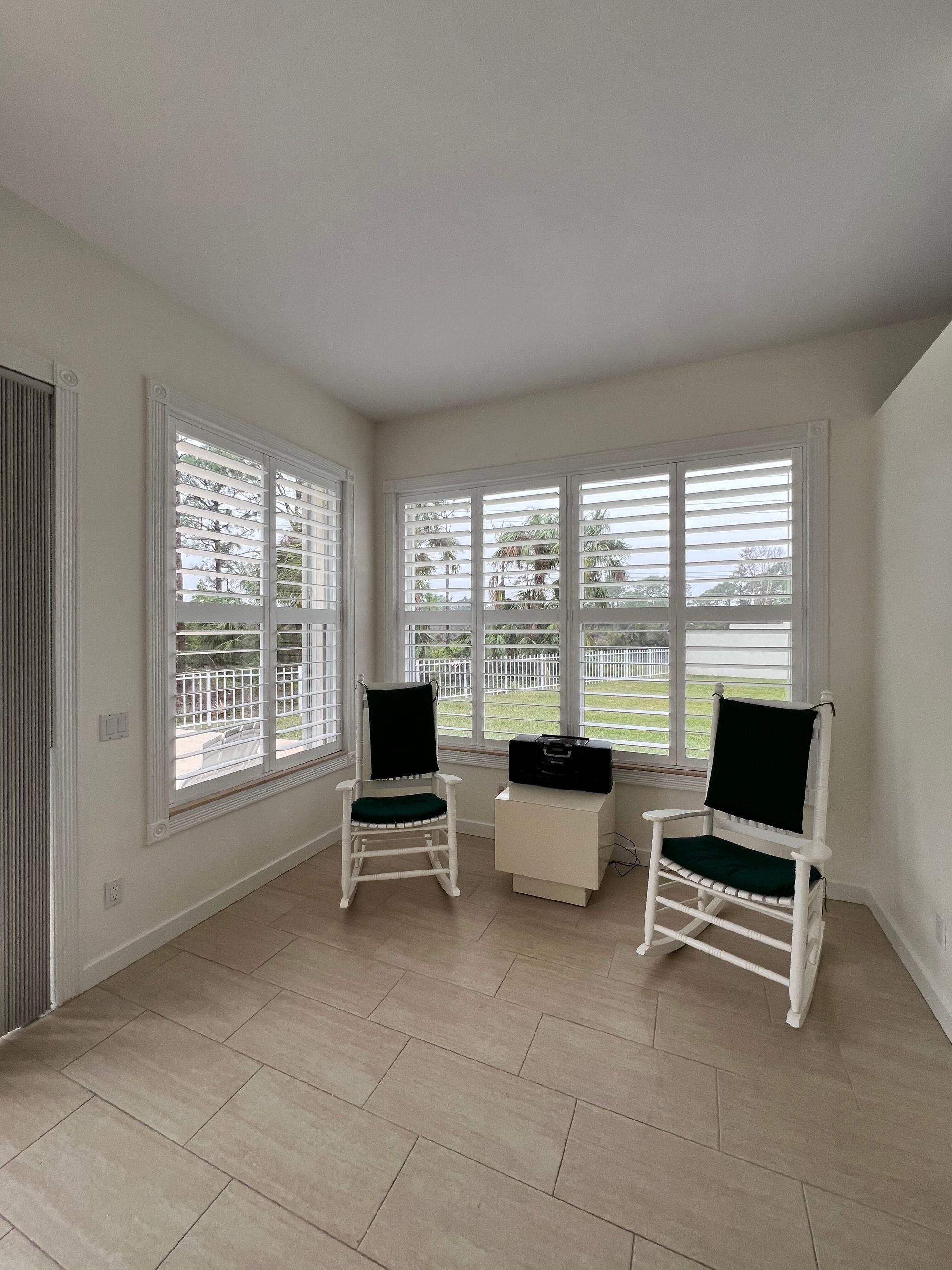 A sunlit sunroom dressed wall-to-wall in white California shutters
